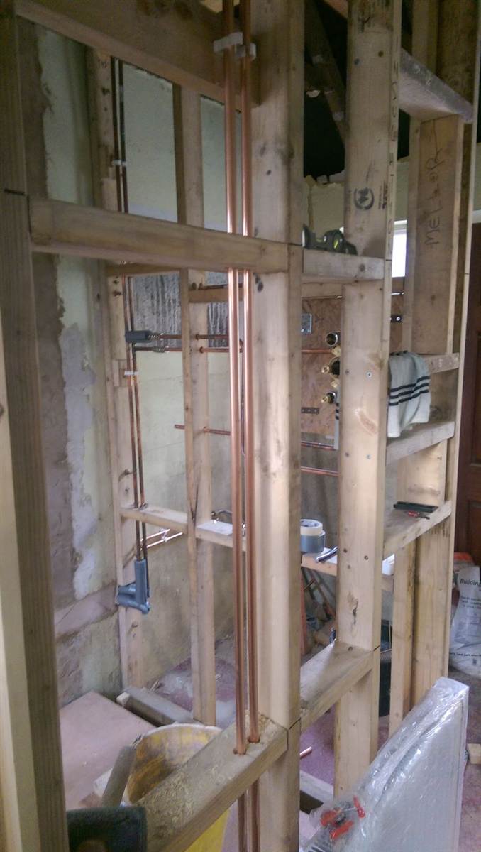 During — stud frame up with copper pipework run through it and shower valve body positioned